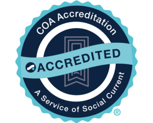 "A COA Accreditation badge with a ribbon across it labeled 'Accredited.' The text around the badge reads 'COA Accreditation - A Service of Social Current.' The badge is set against a solid blue background."